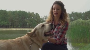 Parktaki gölde kıvırcık saçlı kadın ve labrador köpeği, video. 