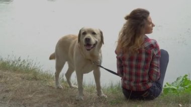 Parktaki gölde kıvırcık saçlı kadın ve labrador köpeği, video. 