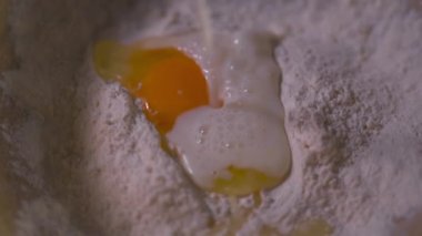 Un üzerine yumurta ile süt dökülür. Düz bir yüzeyde un ve çiğ yumurta, video. 