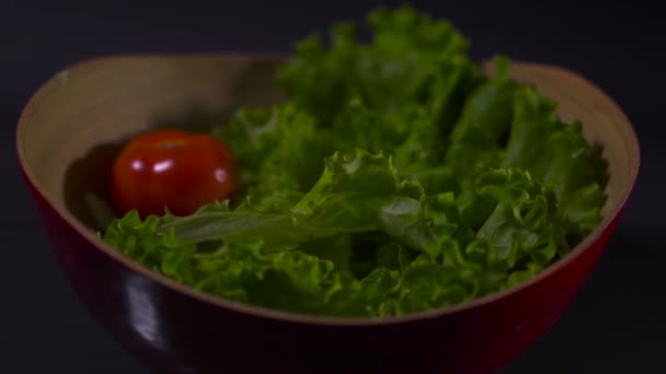 番茄和生菜放在一个碗里 背景是黑色的 半碗西红柿和沙拉一起掉在一个碗里 黑色背景 — 图库视频影像