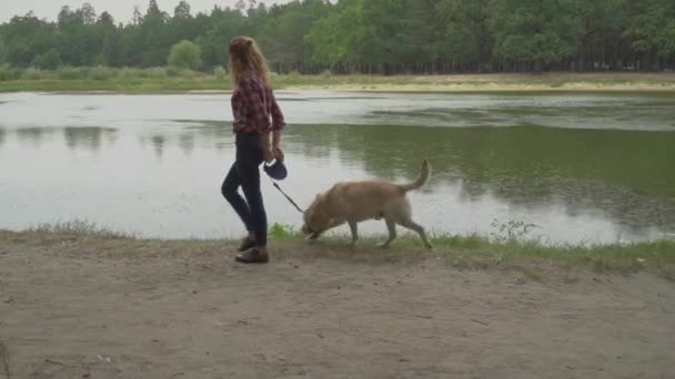 Kıvırcık Saçlı Kadın Köpekle Birlikte Ormanda Göl Kenarında Yürüyor — Stok video