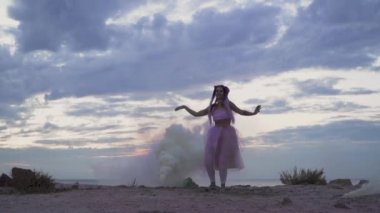 Pembe elbiseli, parlak makyajlı güzel bir kız. Dışarıdaki sis bombalarının dumanında dans ediyor..