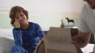 Ağabeyim küçük bir kardeşin kitabını okuyor. Sabahları yatak odasındaki yatağın kenarında oturuyor.