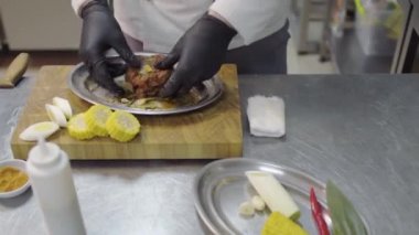 Şef, restoranın mutfağında fırında pişirmeden önce soya soslu çiğ et koyuyor. Sağlıklı yaşam tarzı, yemek hazırlama konsepti. Yakınlarda mısır, sarımsak ve bıçaklar var.