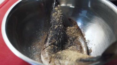Aşçı yakın servis için deniz balığı uskumrusu hazırlıyor. Bütün balık alüminyum yay ile yavaş çekimde baharat serpiştirilmiş. Modern restoranda yemek hazırlığı