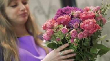 Beyaz kadın çiçekçi güzel çiçekler kokluyor, video klip çekiyor. 
