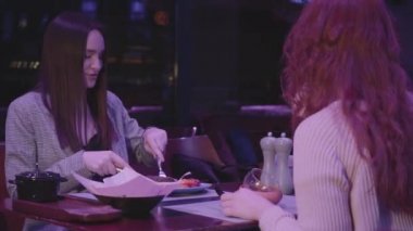 İki tatlı kız arkadaş modern bir restoranda yemek yiyorlar..