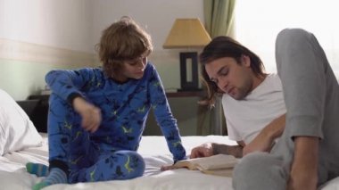 İki kardeş yatağa uzanır, yakışıklı ağabey küçük şirin kardeşe kitap okur ve beşlik çakar..