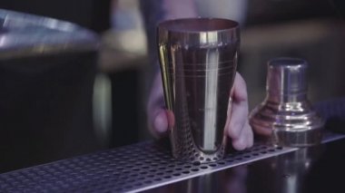 Barmen elinin ölçü kabından bardağa su doldurduğu yakın çekim. Kokteyl hazırlama.