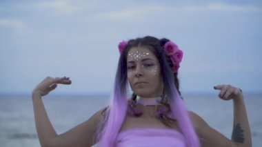 Açık havada dans eden pembe elbiseli, parlak makyajlı güzel kız..