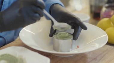 Profesyonel aşçının elleri siyah lastik eldivenli, metal formu kullanarak marine edilmiş çiğ et şeklini alan ve üzerine sos koyan elleri büyük tabağa. Yemek servisi.