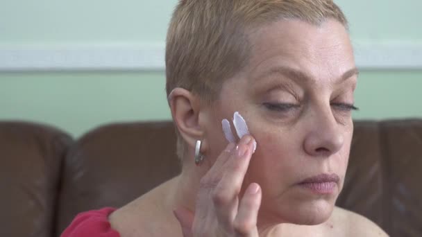 Reife Frau Anwendung Gesichtscreme Auf Gesicht Während Der Blick Auf — Stockvideo