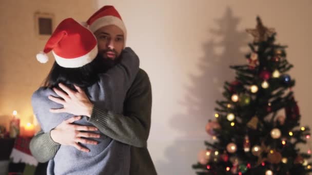 Jonge Positieve Paar Santa Hoeden Dansen Knuffelen Kamer Bij Kerstboom — Stockvideo