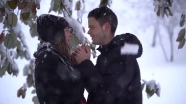 Güzel genç bir kadın ve bir adam kış parkında kar altında, video