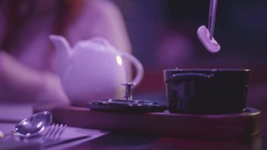 Masa ayarlı restoran masası. Ahşap tabanda çaydanlık ve küçük siyah kâse var. Elleriyle şampiyon mashroom 'u cımbızla kesiyorlar. Arka planda oturan kadın cesedi..