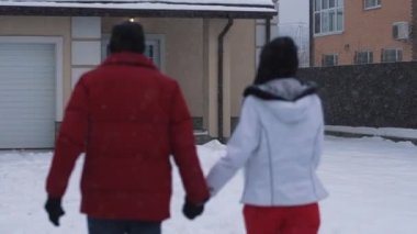 Kadın ve sakallı adamın arka bahçede el ele tutuşup öpüşmelerini gösteren yavaş çekim videosu.