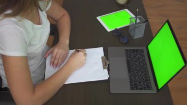 Genç bir kadın ofis masasına oturur, grafik çizer ve çizimleri bilgisayardan kişiye gösterir..
