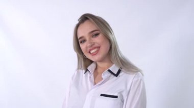 Burnu delinmiş beyaz bluzlu genç bir kadının portresi kameraya yakından gülümsüyor. Ofisteki sarı saçlı bayan stüdyoda. Modern kız mutlu ve pozitif.