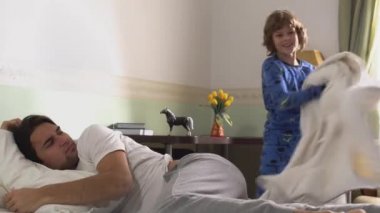 Pijamalı iki kardeş kavga eder ve sabahları yatakta oynaşırlar..