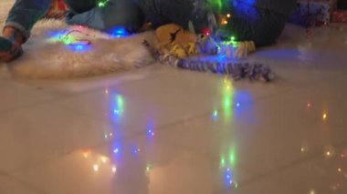 Yeni yıl ağacının yanında oturan erkek ve kadın boynunda bir çelenkle oturuyorlar. Adam çelenk sallıyor, kız yılan gibi büyüyor, noel videosu. 