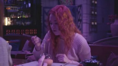 Kabarık kıvırcık saçlı, modern bar ya da restoranda yemek yiyen ve kameraya 