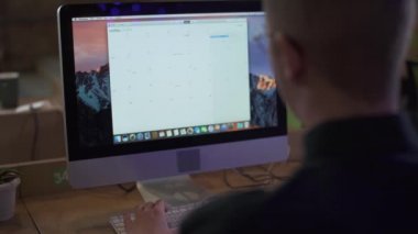 Ofisteki modern bilgisayarın önünde oturan adamın videosu.