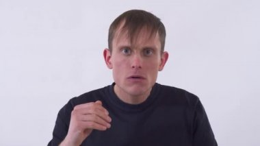 Kameraya bakan olumlu bir adamın portresi Mirrir 'deki gibi saçlarını düzeltiyor ve suratını buruşturuyor. İnsanlar farklı şekillerde ifade eden yüzünü çarpıtıyor ve gülümsüyor. Beyaz bir arka planda stüdyoda çekim yapmak.