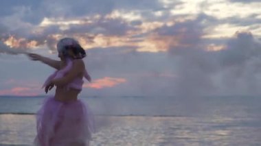 Açık havada sis bombalarıyla dans eden pembe elbiseli güzel bir kız..