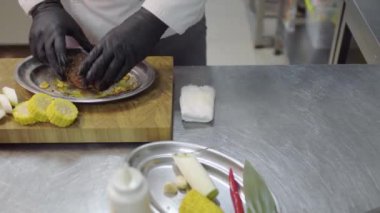 Şef, restoranın mutfağında fırında pişirmeden önce soya soslu çiğ et koyuyor. Sağlıklı yaşam tarzı, yemek hazırlama konsepti. Yakınlarda mısır, sarımsak ve bıçaklar var.