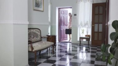 Güzel genç bir kadın eve giriyor, ayakkabılarını çıkarıp atıyor. Yorgun kız eve döndü. Ahşap mobilyalar ve yerde siyah beyaz fayanslar olan güzel bir oda.