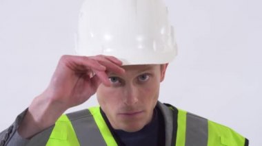 Yakışıklı, kendine güvenen, beyaz arka planda duran beyaz şapkasını tamir eden genç bir adam..