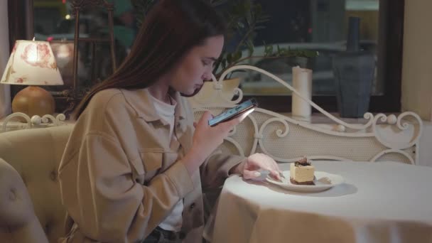 可爱的小女孩在智能手机上拍照 桌上摆放着美味的蛋糕和装饰品 — 图库视频影像