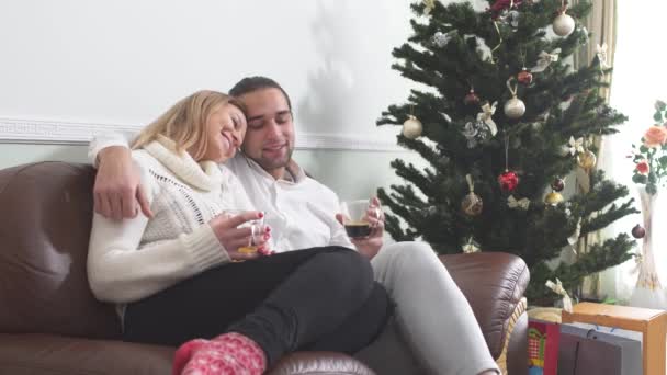 Joven Abrazando Novia Sentada Sofá Tomando Café Junto Árbol Navidad — Vídeo de stock