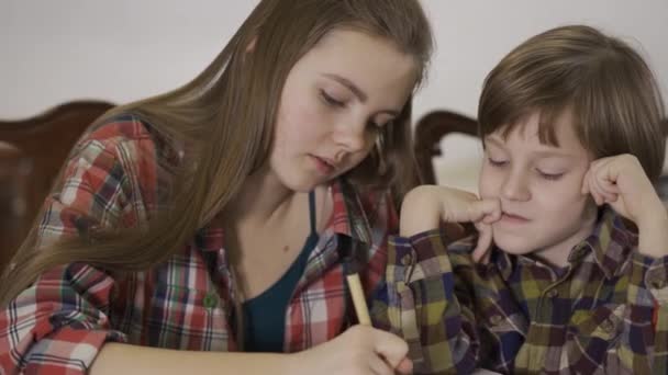Syster Hjälper Sin Bror Med Hemuppgiften Porträtt Två Söta Barn — Stockvideo