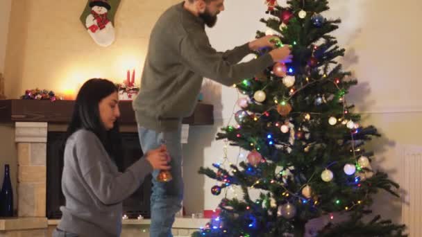 Joven Pareja Positiva Decorando Árbol Navidad Juntos Mujer Dando Juguetes — Vídeos de Stock