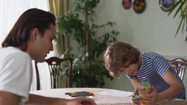 Két Mosolygó Testvér Egy Jóképű Felnőtt Aranyos Kisfiú Játék Asztalon — Stock videók