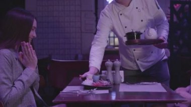 Tanınmayan şef mavi ışıkta bir gece kulübünde ya da restoranda masada oturan iki kız için yemek getiriyor. Güzel kız arkadaşlar birlikte eğlenin.