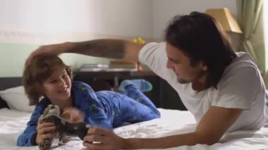 Büyük ve küçük kardeşler birlikte eğleniyorlar. Yatakta yatan iki kardeş kaplan ve atla oynuyor..