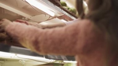 Küçük kız süpermarkette annesine yardım ediyor. Annemle süpermarkette küçük bir kız. Kızı, annesine dükkanda yardım ediyor. Güzel siyah saçlı anne ve küçük kızı marketten yiyecek alıyor.