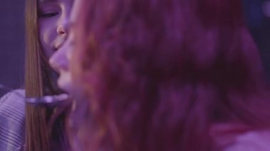 İki kız arkadaş modern bir restoranda birlikte akşam yemeği yiyorlar. Esmer kadın kızıl saçlı kız arkadaşını besliyor ve mutlu bir şekilde gülümsüyor. Restoranda yemek yiyen lezbiyen çift.