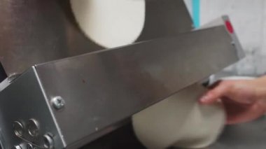 Şefin elleri, yakın çekimde özel metal makine kullanarak ince hamurlar elde etmek için hızlı çalışır. Modern restoranda lezzetli yemek hazırlığı. Mutfakta çalışan yetenekli bir adam.