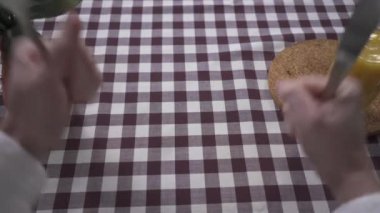 Adamın eli masaya çatal ve bıçakla yumruklarıyla vuruyor ve yemek istiyor. Kareli masa örtüsünde yumurtalı tabak belirdiğinde insan yemeye başlar. Beslenme kavramı. İlk ateş eden kişi.