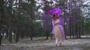 Pembe elbiseli, parlak makyajlı güzel bir kız. Arka planda sis bombalarıyla dans ediyor..