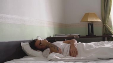 Pijamalı uykulu adam istemeyerek yataktan çıkıyor.