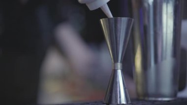 Barmen elini yakın çekim şişeden ölçü kabına su dökerken çek. Kokteyl hazırlama.