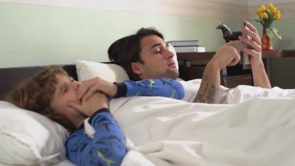 Δύο Χαριτωμένα Κουρασμένα Αδέρφια Ξαπλώνουν Στο Κρεβάτι Καλυμμένα Λευκή Κουβέρτα — Αρχείο Βίντεο