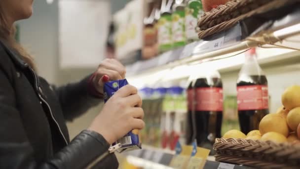 一个女孩在超级市场的货架上喝果汁就走了 商店里的小偷 食品杂货店的隐蔽摄像头 — 图库视频影像