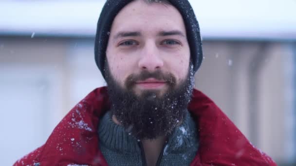 穏やかな髭を生やした男がカメラを閉じて屋外で雪を降らせゆっくりと動き — ストック動画