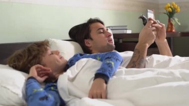 Sabahları pijamalı iki kardeş yatak odasında uzanıyorlar. Büyük kardeş cep telefonuyla mesajlaşırken küçük kardeş yakınlarda..