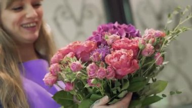 Çiçek buketiyle gülümseyen çiçekçi kız. Elinde bir demet çiçek ve video tutan güzel kız. 